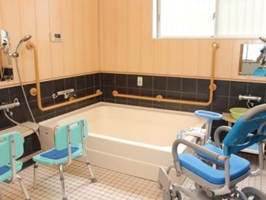 座ったまま入浴できるシャワーチェアや車いすが置いてある介護仕様の浴室の様子