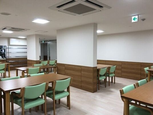 四人掛けのテーブルと椅子が並べられている様子。施設内の食堂の写真