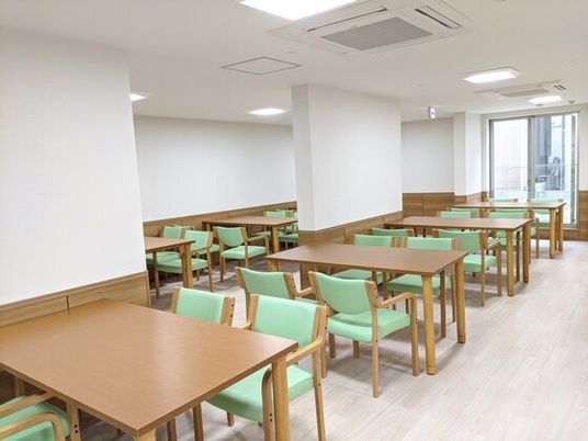 四人掛けのテーブルと椅子が並べられている施設内の食堂の様子