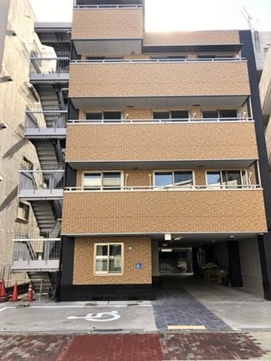 5階建ての建物はブラウン系で重厚感があり、建物の前には駐車場もある。