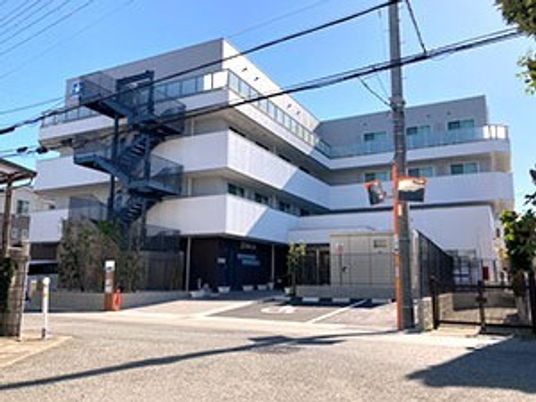 4階建ての建物は白を基調としたデザインで日当たりのいい場所に建っている。駐車場もある。