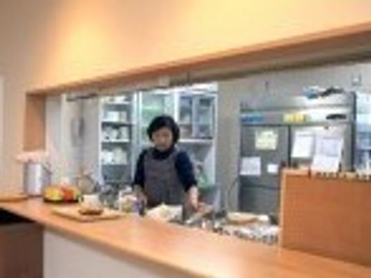 スタッフがエプロンをしてキッチンで作業をしている様子。対面キッチンはオープンな造り。