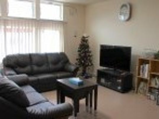 黒ソファがテーブルを囲むようにして置かれたリビングには、大きなテレビもある。