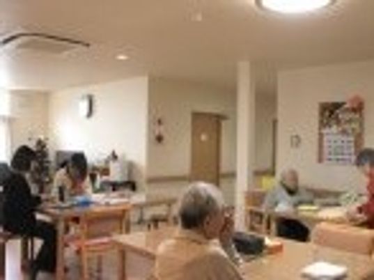 ダイニングテーブルが複数並び、思い思いの場所で過ごしている入居者とスタッフ。