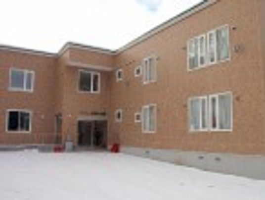 レンガ調の外壁が明るい雰囲気の２階建ての建物。敷地が広い。