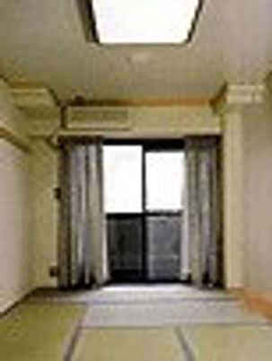 小さな部屋の向こう側に窓が見えている。照明があるのが写っている写真