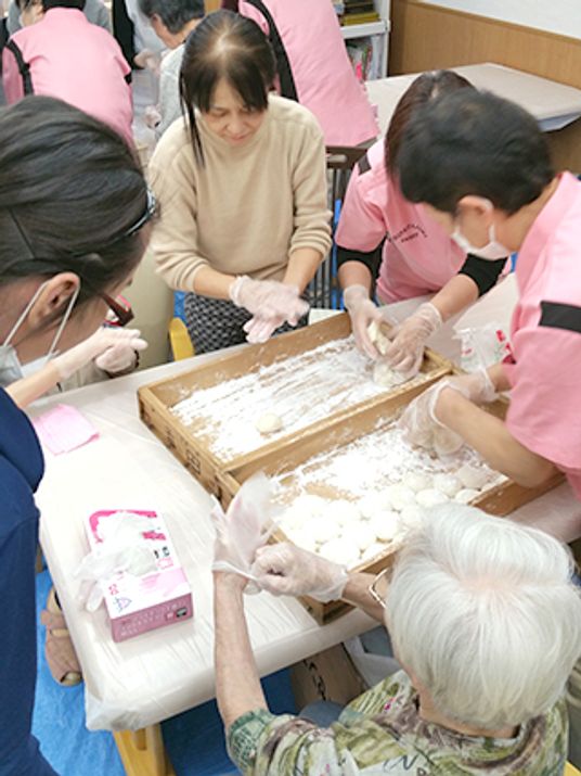 高齢者とスタッフがお菓子作りをしている様子。施設内レクリエーションのひとつ