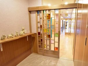 ステンドグラス風のガラス戸が設置されたエントランス周辺にある棚には猫の置物がたくさん置かれ、アットホームな雰囲気。