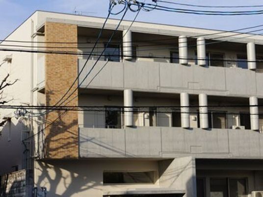 ライトグレーの3階建ての建物には一緒にがあり、外壁の一部はレンガ調。日当たりにいい場所にある。