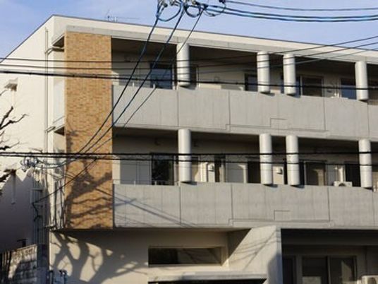 ライトグレーの3階建ての建物には一緒にがあり、外壁の一部はレンガ調。日当たりにいい場所にある。