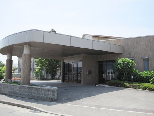 大きな車寄せが付き、重厚感のある玄関。周辺には緑がある。