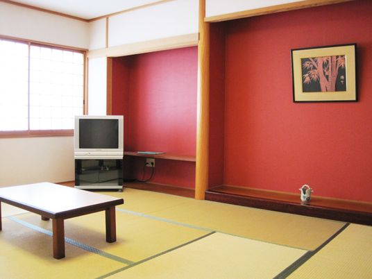 朱色の壁が印象的なゲストルームには床の間もあり、テレビやテーブルもある和室となっている。