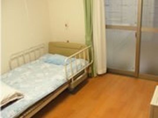 フローリング仕様の小さな部屋の様子。窓やベッドが写っている