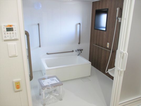 洗い場が広い浴室にはたくさんの手すりや呼び出しボタンが付き、３方向から介助可能な位置に浴槽が設置されている。