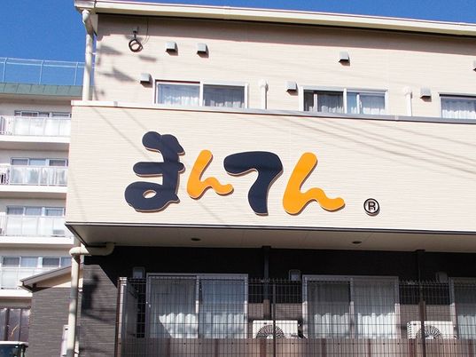 ２階建ての建物はベージュで道路に面して建てられていて、ベランダ部分にホーム名が書かれている。