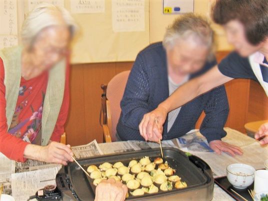 たこ焼きを楽しんぢL高齢者とスタッフ。施設内の食のイベントの様子