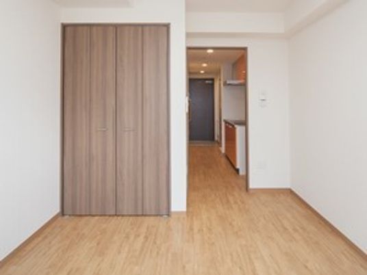 フローリングの居室は段差がなく、キッチンが付いている。窓が輪から居室全体を見渡した様子。