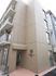 4階建てのブラウンを基調とした建物は一般のマンションのようなたたずまい。玄関横には住宅のロゴがある。