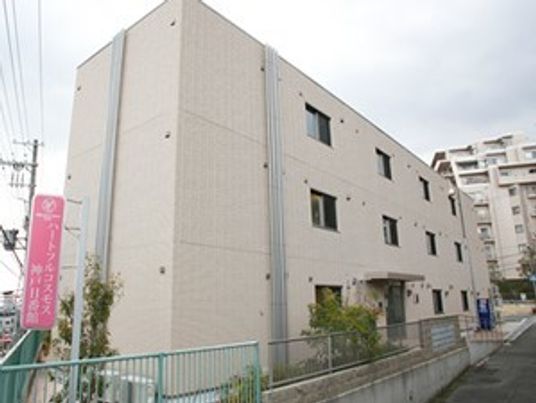 白を基調とした３階建ての建物横にはピンクの看板が設置され、玄関近くには自動販売機も設置されている。