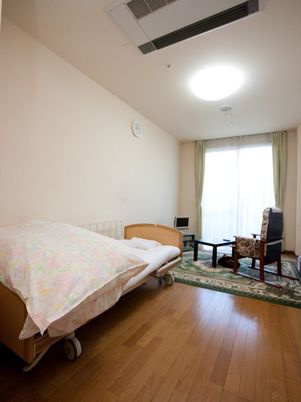 ベッドが置かれた居室にはカーテンが設置された窓もつき、フローリングで明るい雰囲気である。