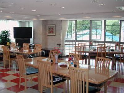 赤と白のフロアの明るい雰囲気の食堂には木製のダイニングテーブルが複数置かれ、テレビも設置されている。