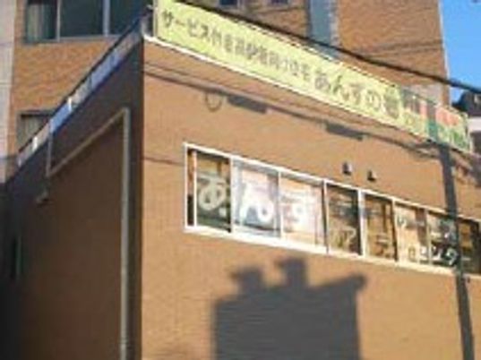 ブラウン系の建物の屋上の垂れ幕や窓には住宅や併設事業所の名前が書かれている。