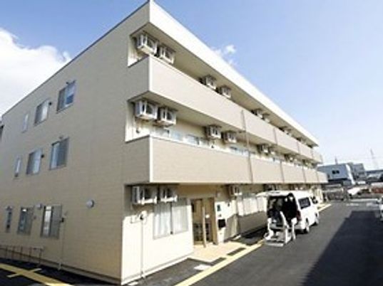 ３階建ての建物が打つている写真。マンションのような建物
