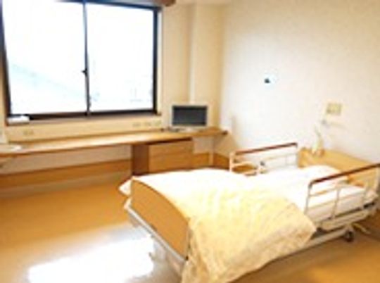 介護用ベッドやそのほかの生活用品が置いてある施設内の小さなワンルームの様子