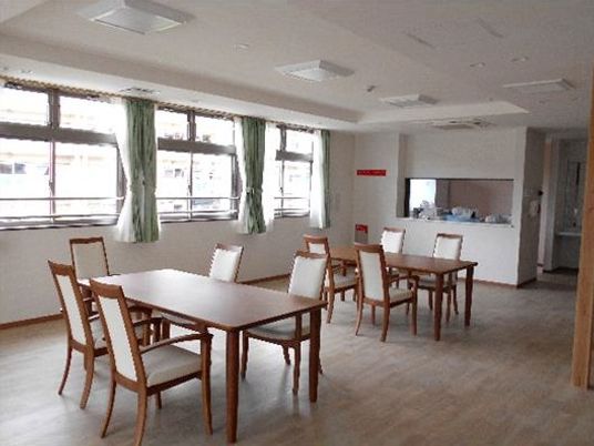 日当たりがいい食堂は対面式キッチンでさりげない見守りが可能。ダイニングテーブルが二つ置かれている。