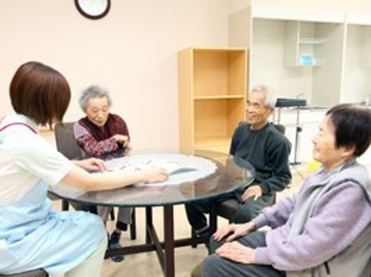 丸いテーブルを囲み談笑をする入居者3名と女性スタッフ。