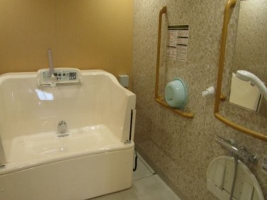 介護用の浴槽を設置した浴室。エル字型の手すりが複数ある安心の設計。