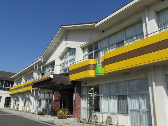 学校を改装した建物は懐かしい雰囲気。2階建てで1階と2階の間には黄色とブラウンのラインが入っている。