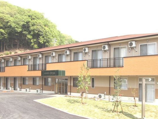 オレンジ系の2階建ての建物。建物周辺には自然があふれている。