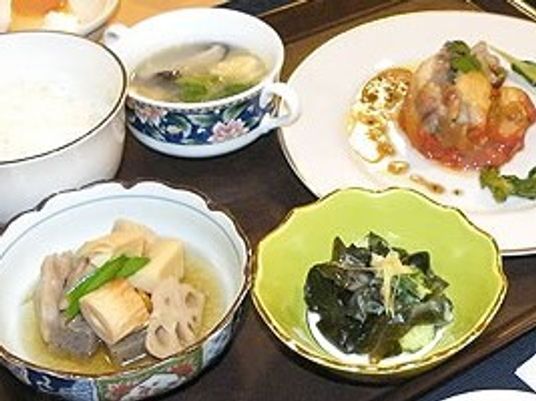 スープにわかめのおひたし、白いご飯、根菜の煮物、洋風のメインが並んでいる食卓。