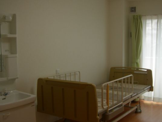 レースカーテンとカーテンが付いた部屋には介護ベッドや洗面所がある。