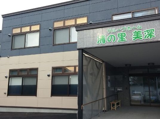 2階建ての建物は黒とベージュで玄関には車寄せが付き、緑の文字でホーム名が書かれている。