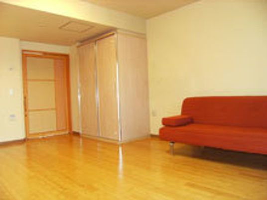 赤い大きなソファが置かれた居室。大型の収納家具もあり、すっきりとした部屋。