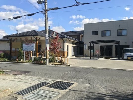 道路に面した二つの建物。２階建ての建物は白く、すぐ隣にある和風の建物は平屋建て。