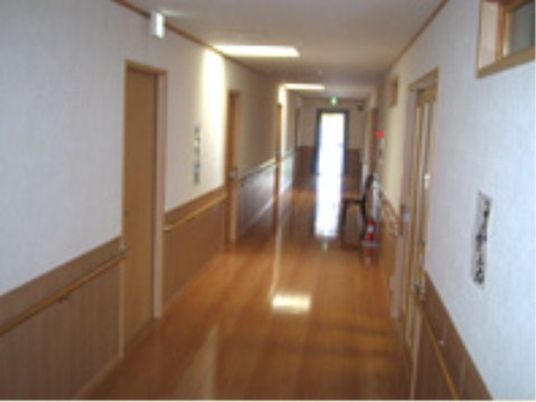 まっすぐに伸びた廊下の突き当たりには窓があり大変明るい。両サイドに居室があり、消火器やいすもある。