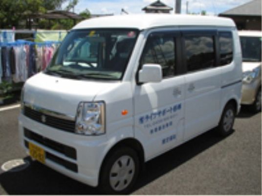 駐車場に止められた白いワゴン車にはホームの名前が書かれている。