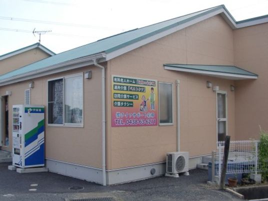 ベージュを基調とした建物は平屋建ててで、玄関周りには自動販売機が置かれている。