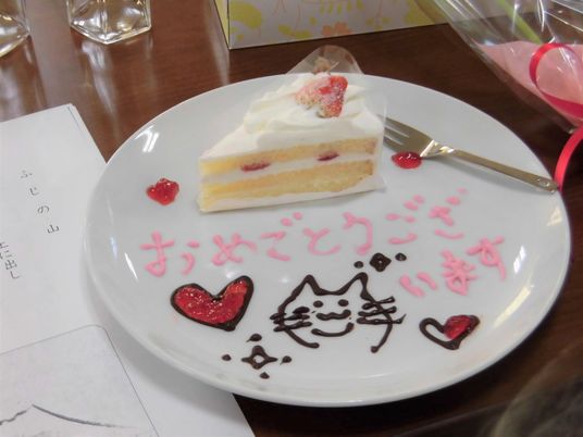 ショートケーキが乗った白いプレートにはチョコペンで猫やハート、「おめでとうございます」と書かれている。