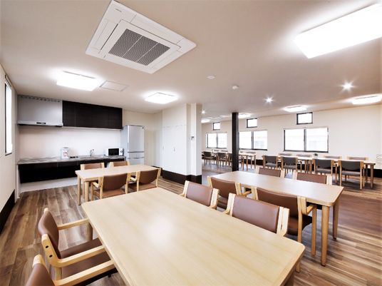 広々としたフローリングの食堂には複数の木製のダイニングテーブルが並び、オール電化のキッチンもある。