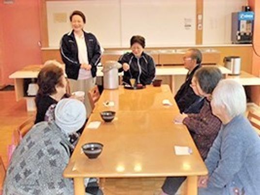 抹茶を囲んだ茶話会の様子。スタッフが抹茶を立て、入居者が待っている。
