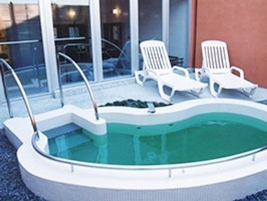 プールのような形の露天風呂には階段もつき、奥には休憩用の椅子が2脚置かれている。