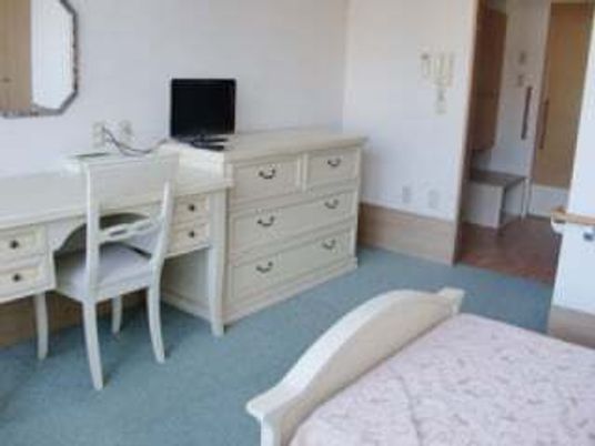 寝具付きのベッドやタンス、デスクセットなどが付いた部屋には大きな鏡もある。