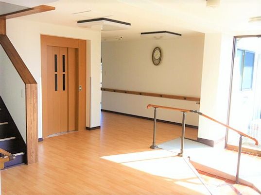 ゆるやかなスロープが付いた玄関内部。入ってすぐの場所にエレベーターと階段が設置され、日当たりのいい館内。