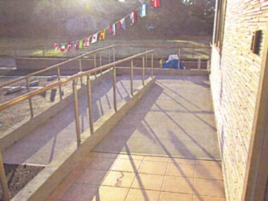 玄関先のスロープには手すりが付き、周辺には緑が多くある。