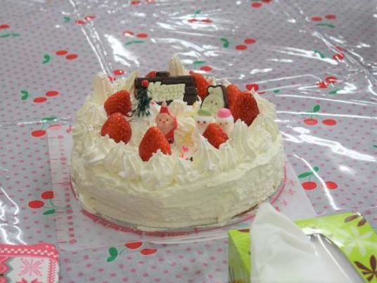 サクランボのテーブルクロスの上にはイチゴやサンタクロースが乗ったクリスマスケーキ。白い生クリームもたっぷり。