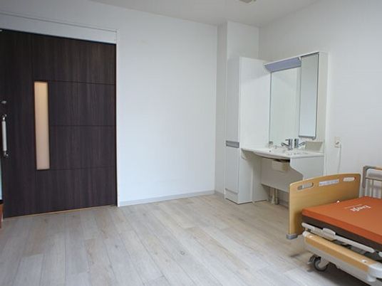 車いす対応の洗面所が設置されたフローリングの部屋には介護ベッドも置かれている。